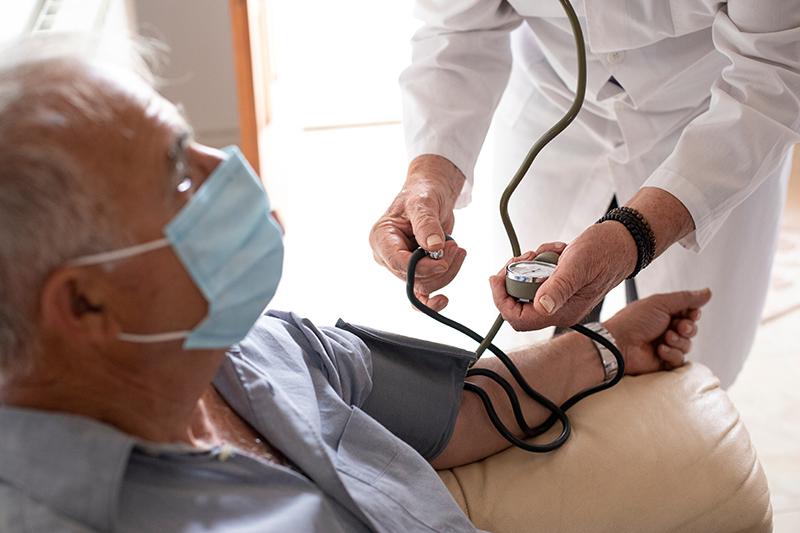 Anziano con mascherina viene visitato da un medico a casa che gl